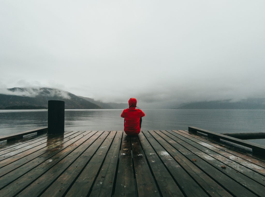 a person sitting alone in front of a lake